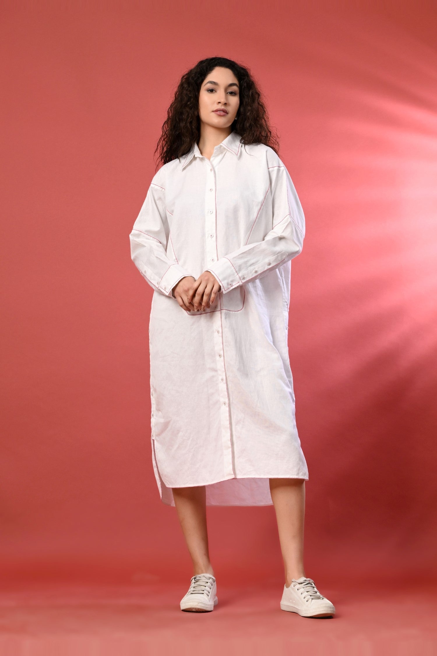 A full-sleeve white long linen shirt dress with intricate thread detailing and a high-low hemline. Lightweight flowy dress
