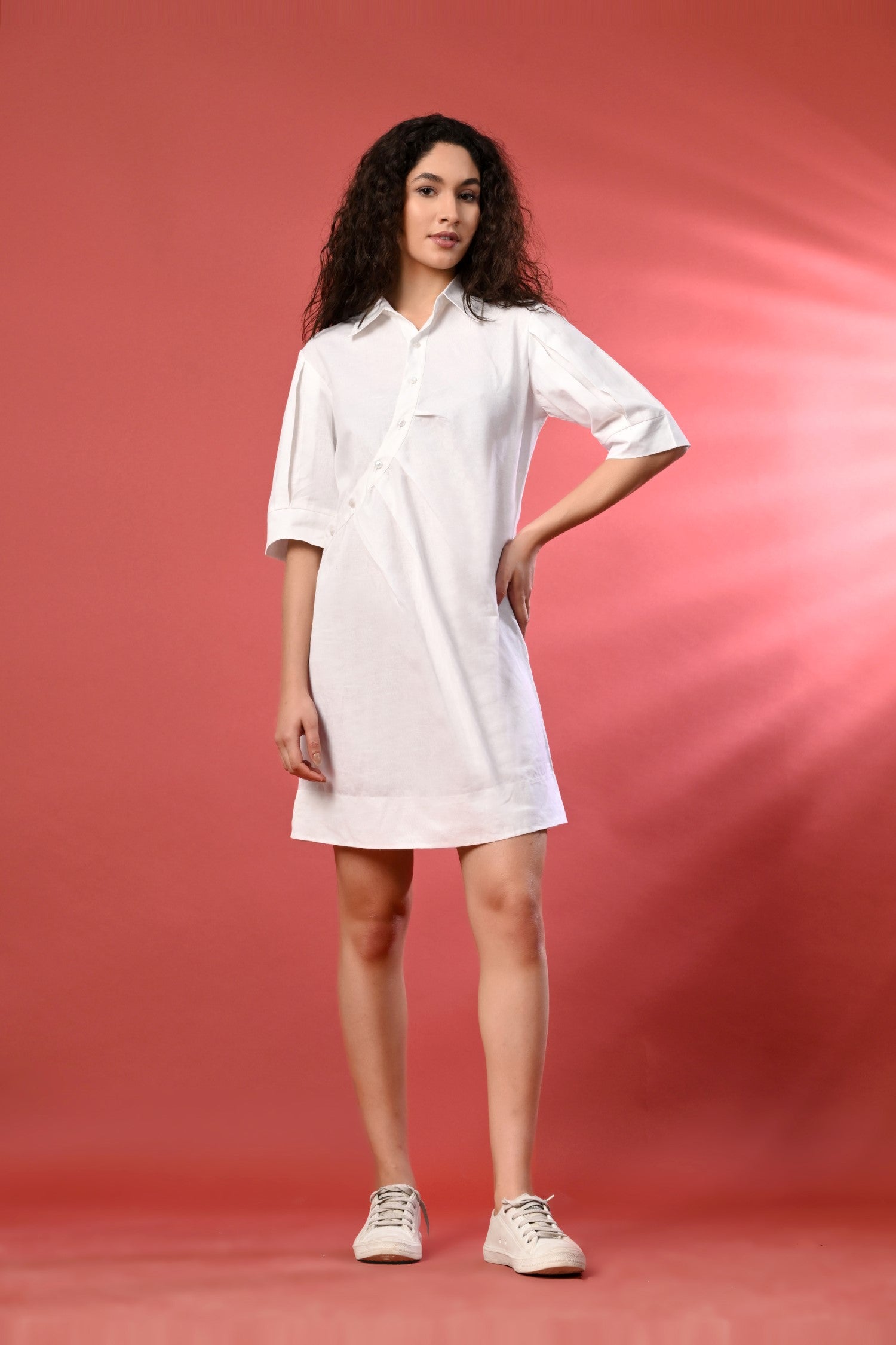 White one-piece linen dress with fine thread detailing, featuring a flowy, breathable silhouette. Styled in a bright, summery