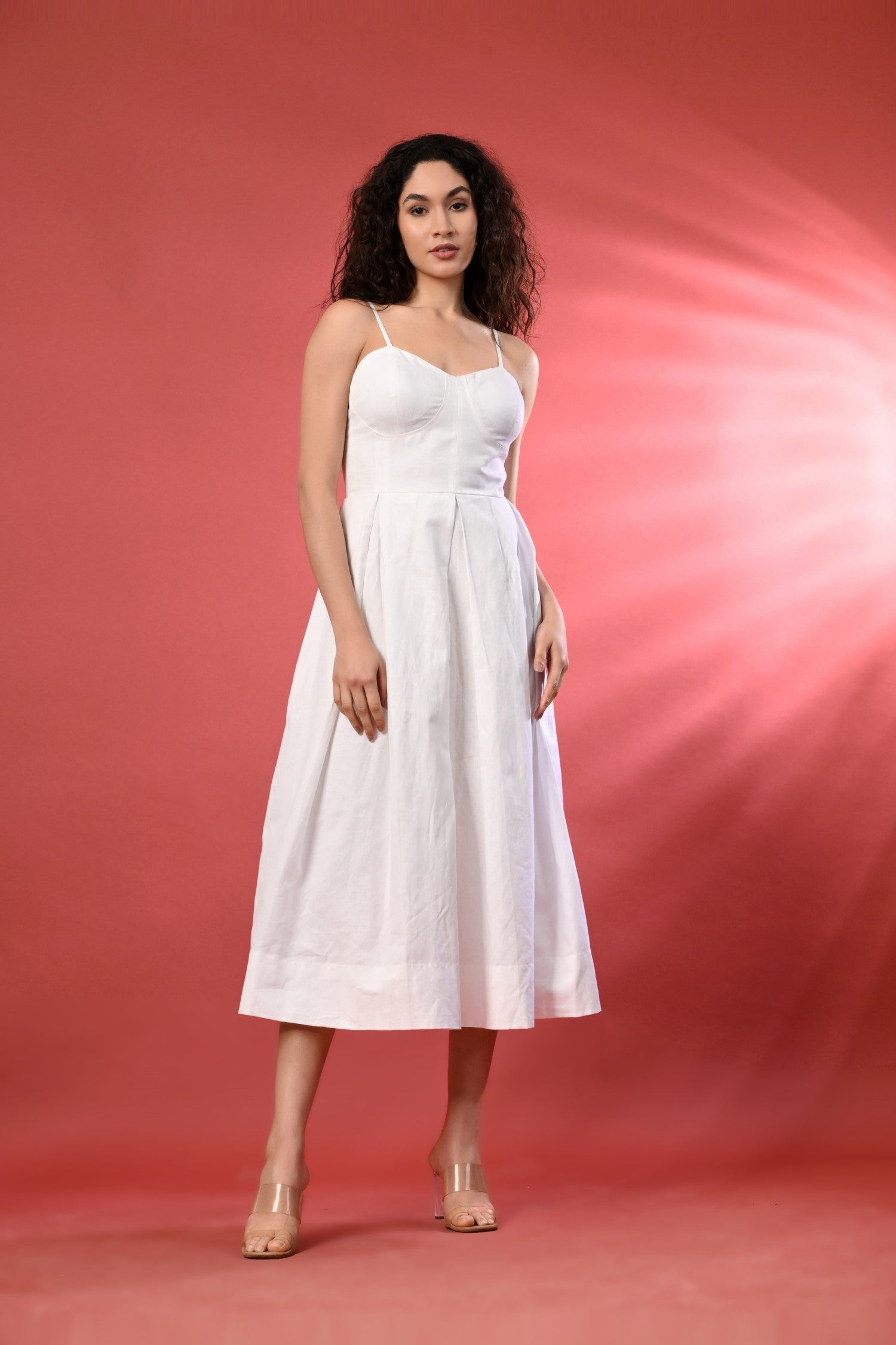 Sleeveless white linen dress with delicate thread detailing styled in a bright, summery setting. The dress features a relaxed